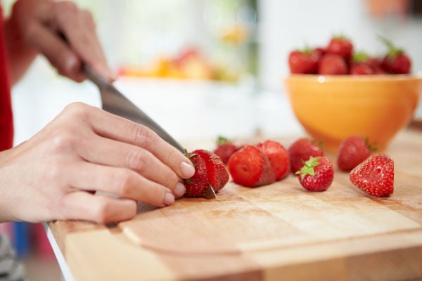 Hulling strawberries on a choppong board