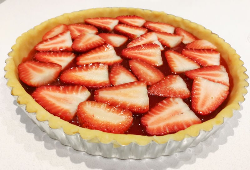 Fresh strawberries layered over jam in a shortcrust tart pan