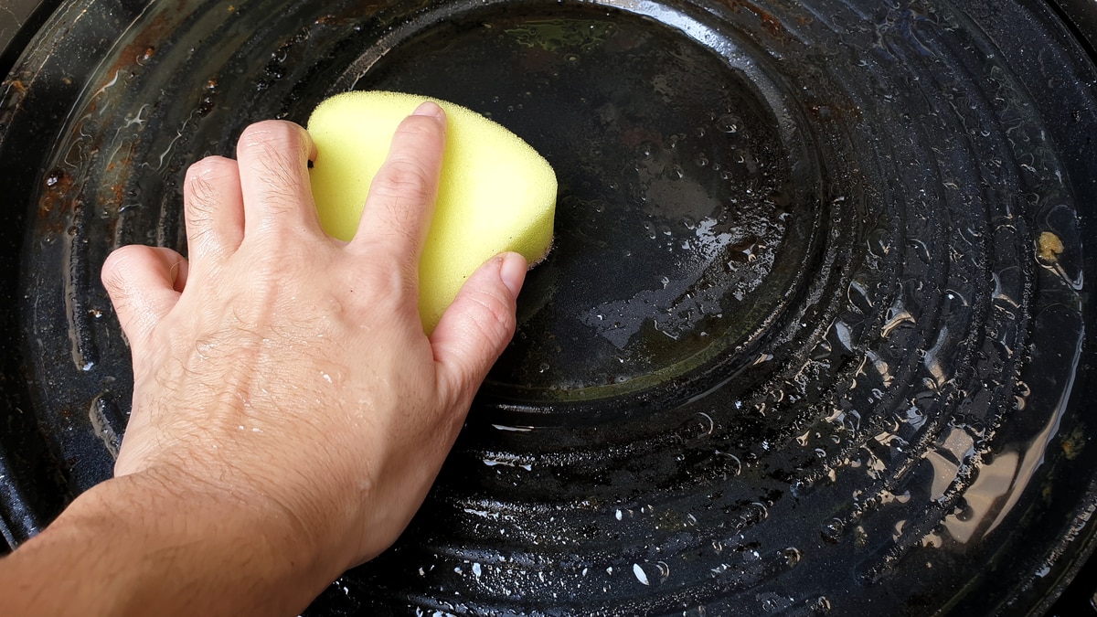Cleaning sponge scrubbing bottom of cast iron frying pan