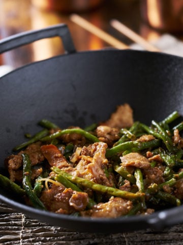 Large cast iron wok cooking chicken and string bean stir fry