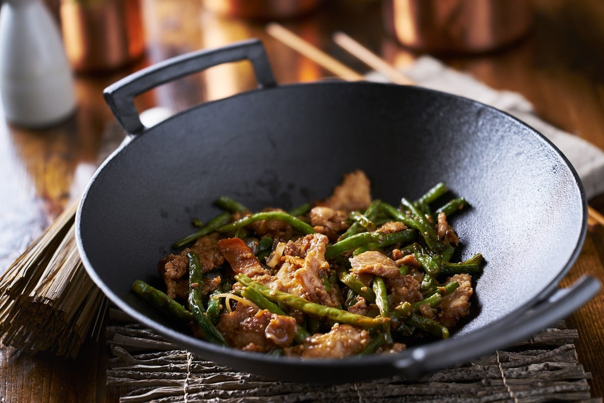 https://tastylicious.com/wp-content/uploads/2021/08/large-cast-iron-wok-cooking-chicken-and-string-bean-stir-fry.jpg