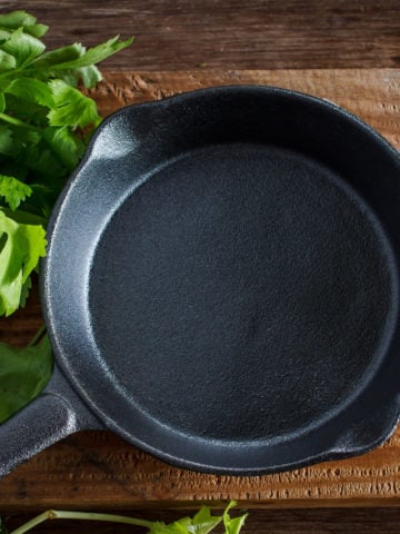 Vintage cast iron skillet on rustic wood background with vegetable prepare for cook