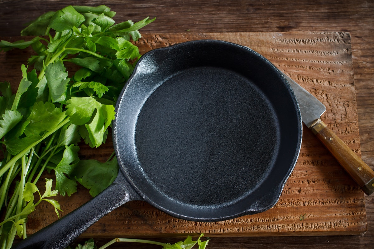 Vintage cast iron skillet on rustic wood background with vegetable prepare for cook