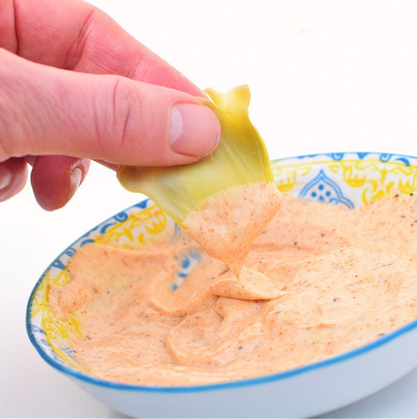 Dipping artichoke bract into a mayo, mustard, and paprika dip