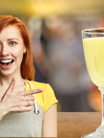 A lady pointing to a glass of advocaat in a bar