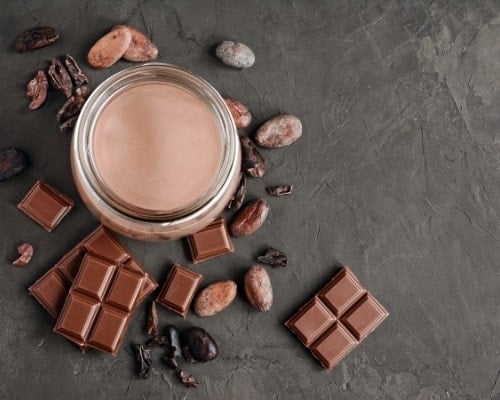 Chocolate Milk With Pieces Of Chocolate Bar And Cacao Beans