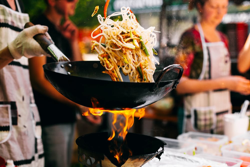 man cooks noodles using a wok