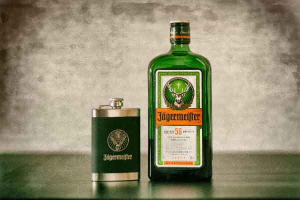 A bottle of Jagermeister next to a hip flask