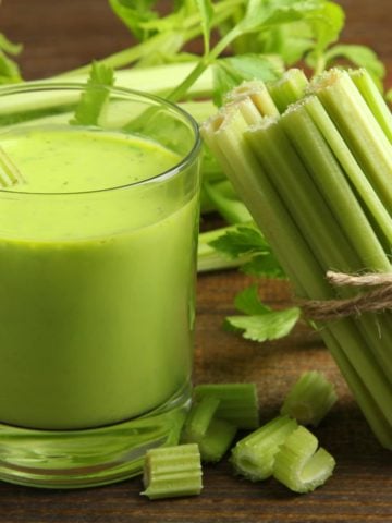 a glass of pure celery juice with fresh celery stalks