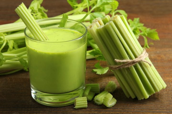 a glass of celery juice with fresh celery stalks