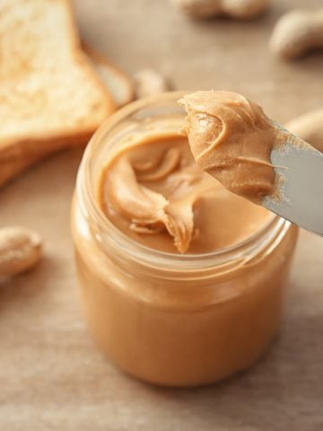 a jar of creamy peanut butter with a bread knife