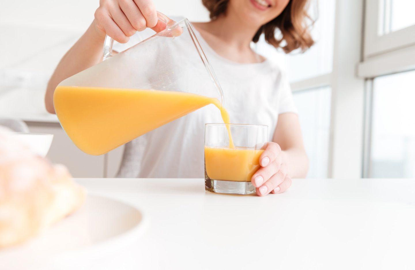 Woman Pouring Orange Juice Into Glass