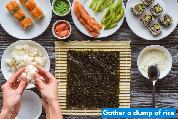 Holding a clump of rice next to seaweed paper