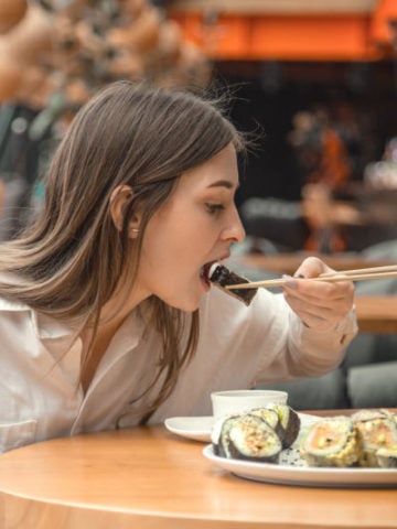 A woman eating sushi at a restaurant