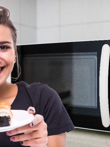 A woman holding a plate of maki rolls next to a microwave