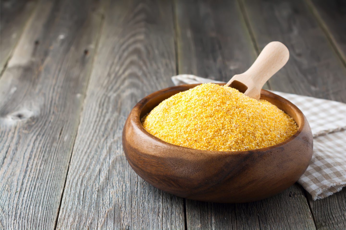 corn grits in small wooden bowl with wooden spoon