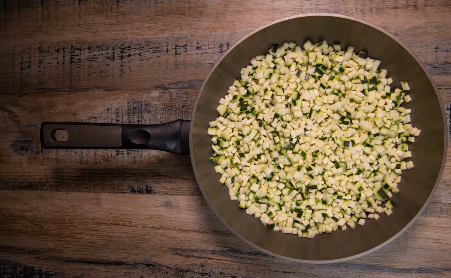 chopped raw zucchini in wooden bowl