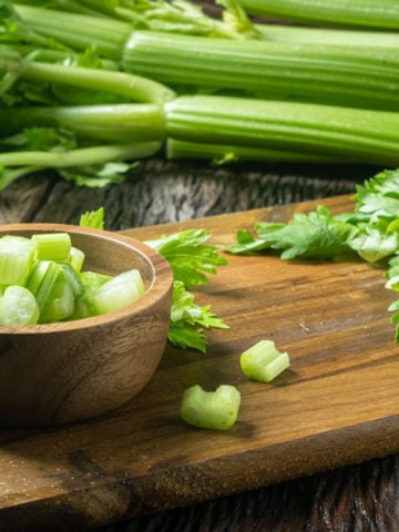 diced celery in a bowl with fresh celery stalks in the background