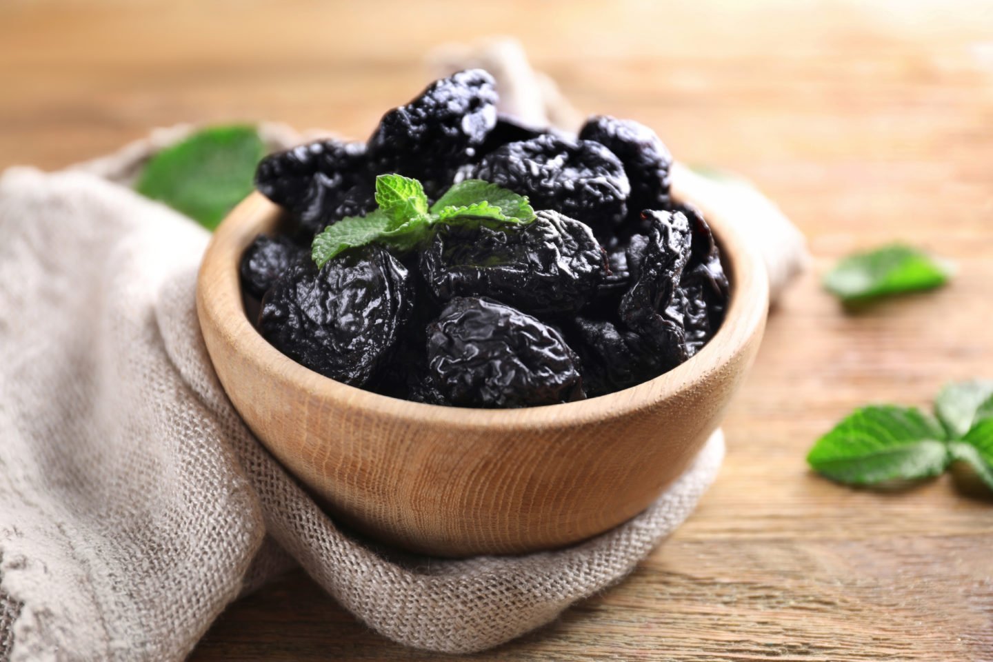 dried prunes in a wooden bowl