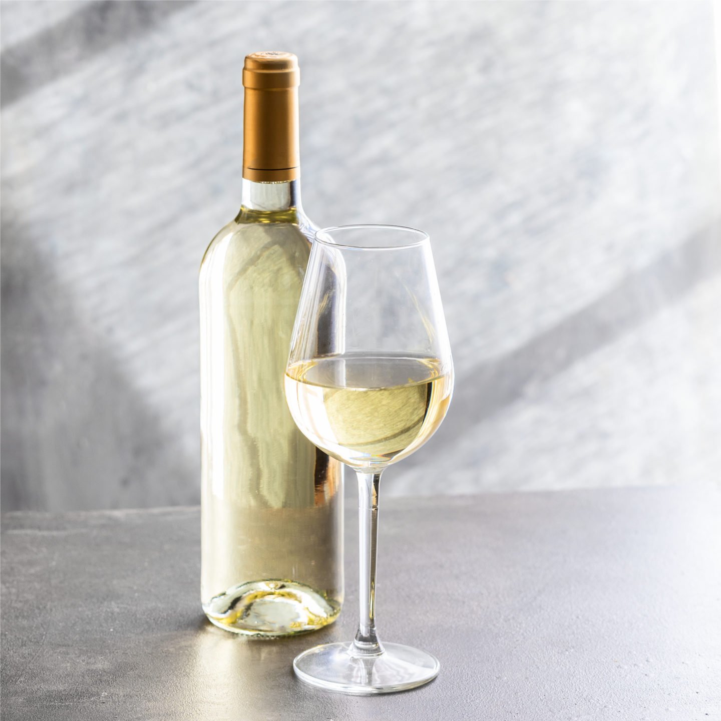 glass of white wine beside bottle