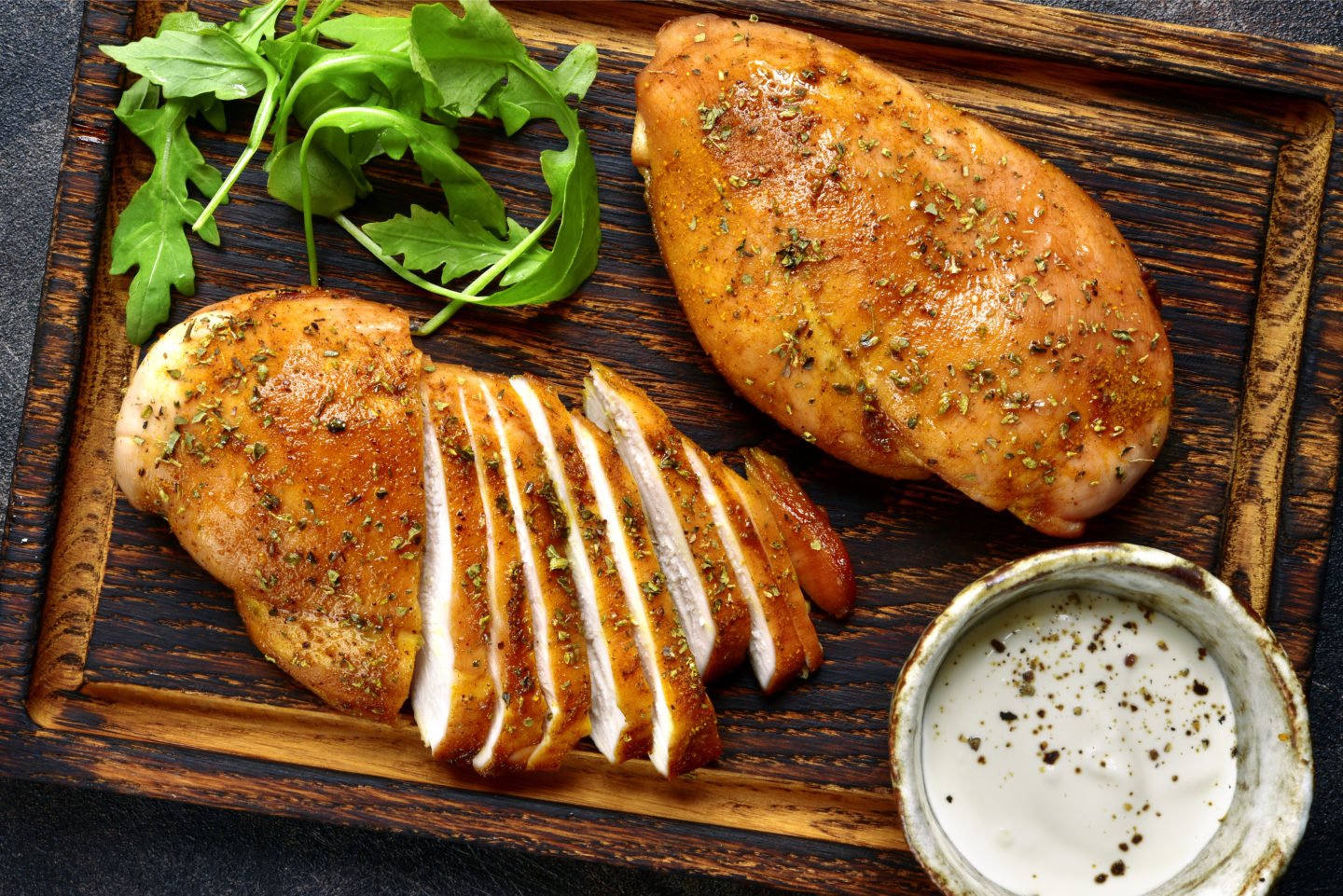 grilled chicken breasts on cutting board with dip