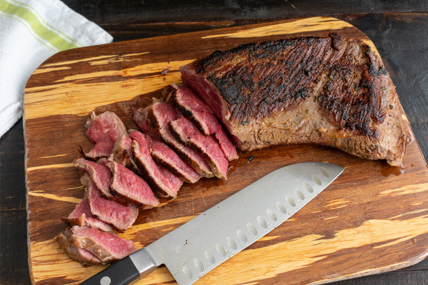 sliced of grilled rare tri-tip steak on cutting board
