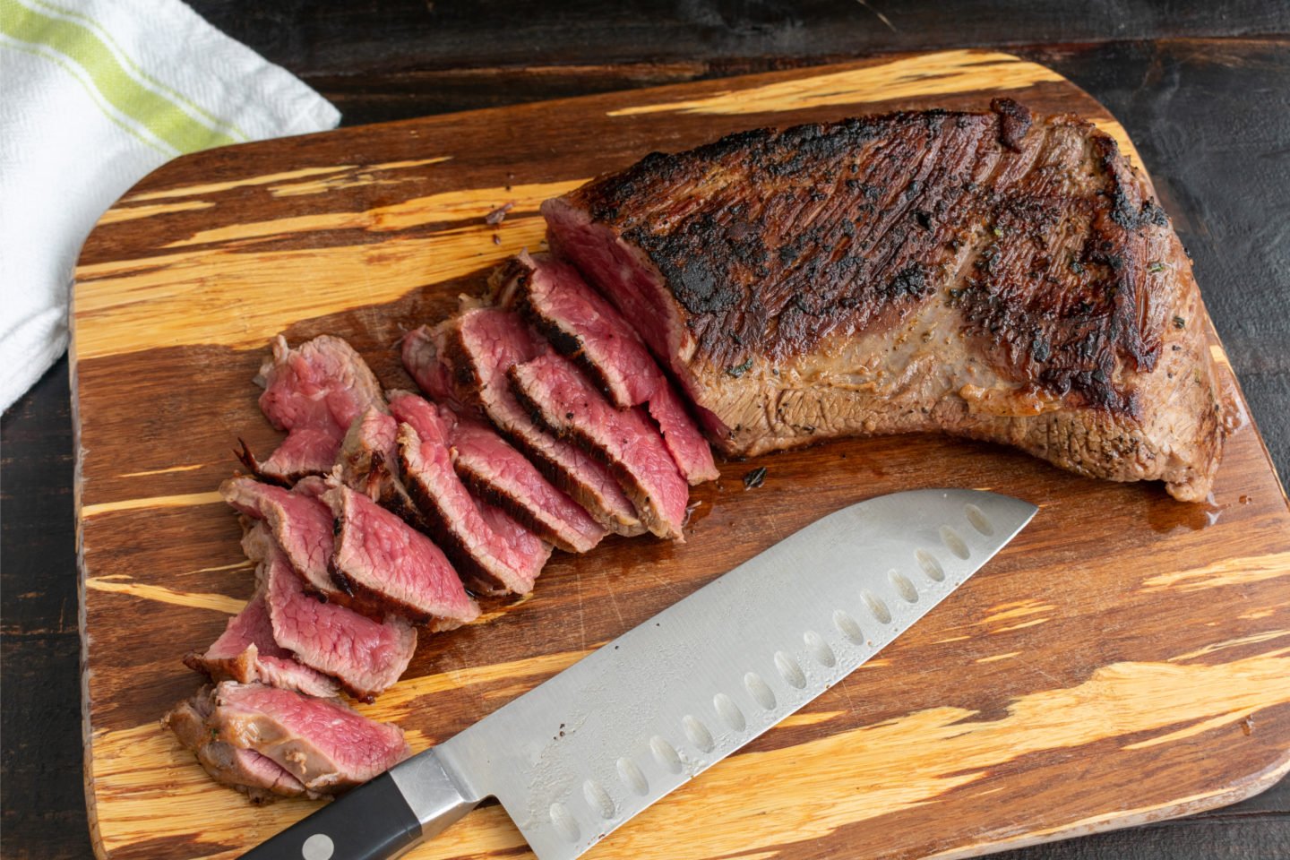 sliced of grilled rare tri-tip steak on cutting board