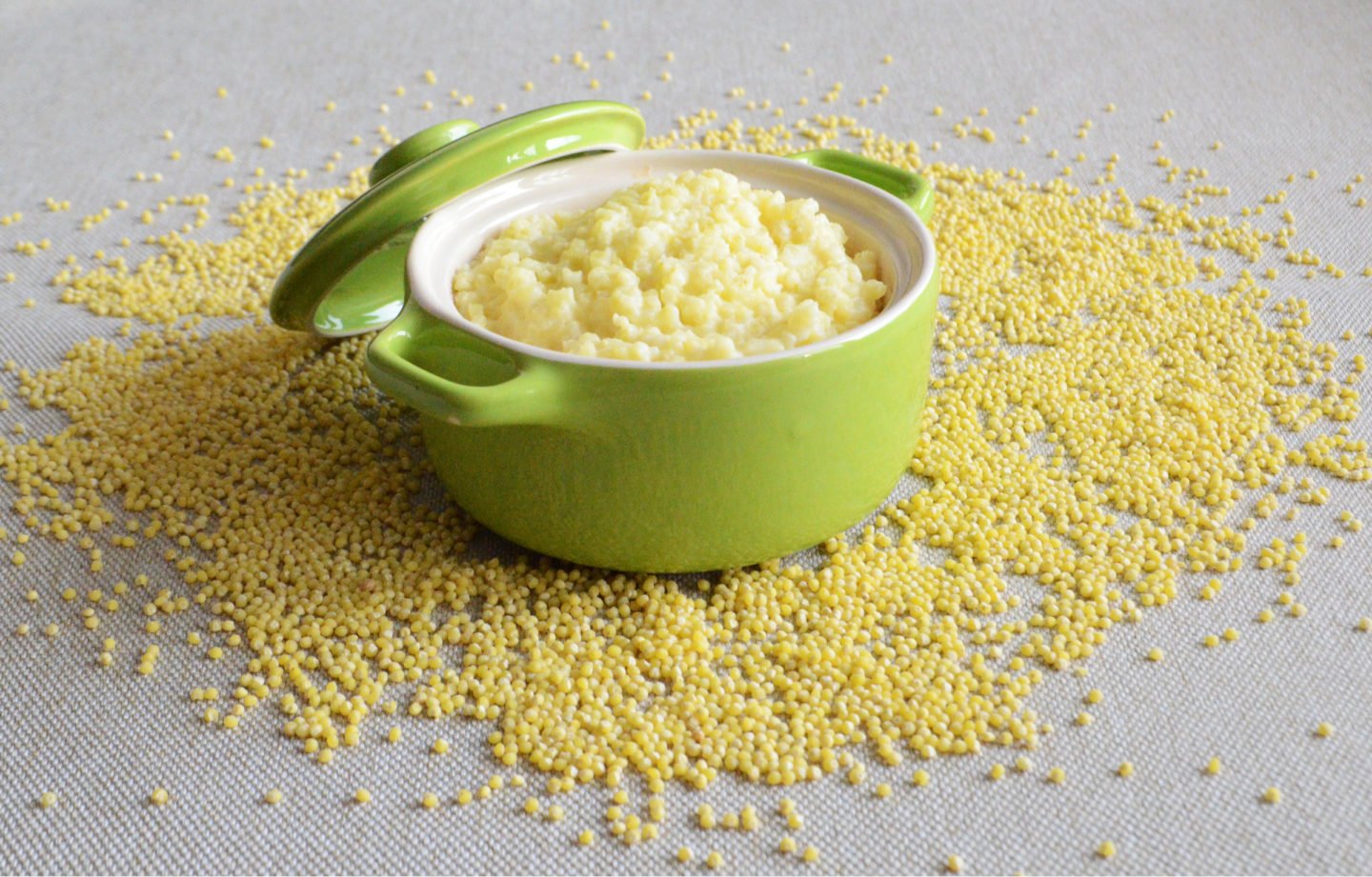 a bowl of millet porridge on top of scattered millet grains