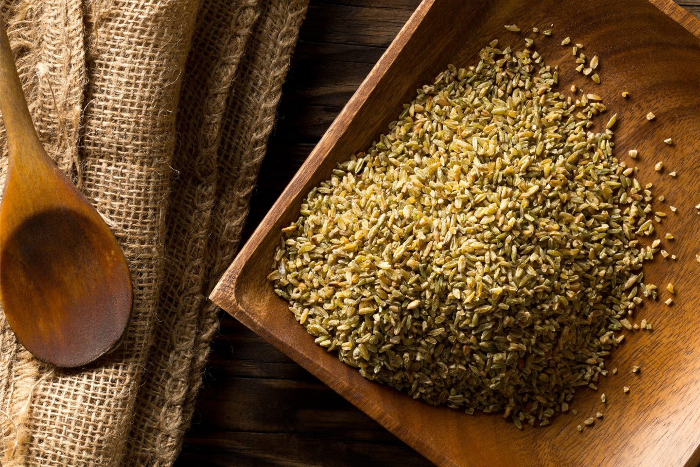 uncooked freekeh piled on wooden tray