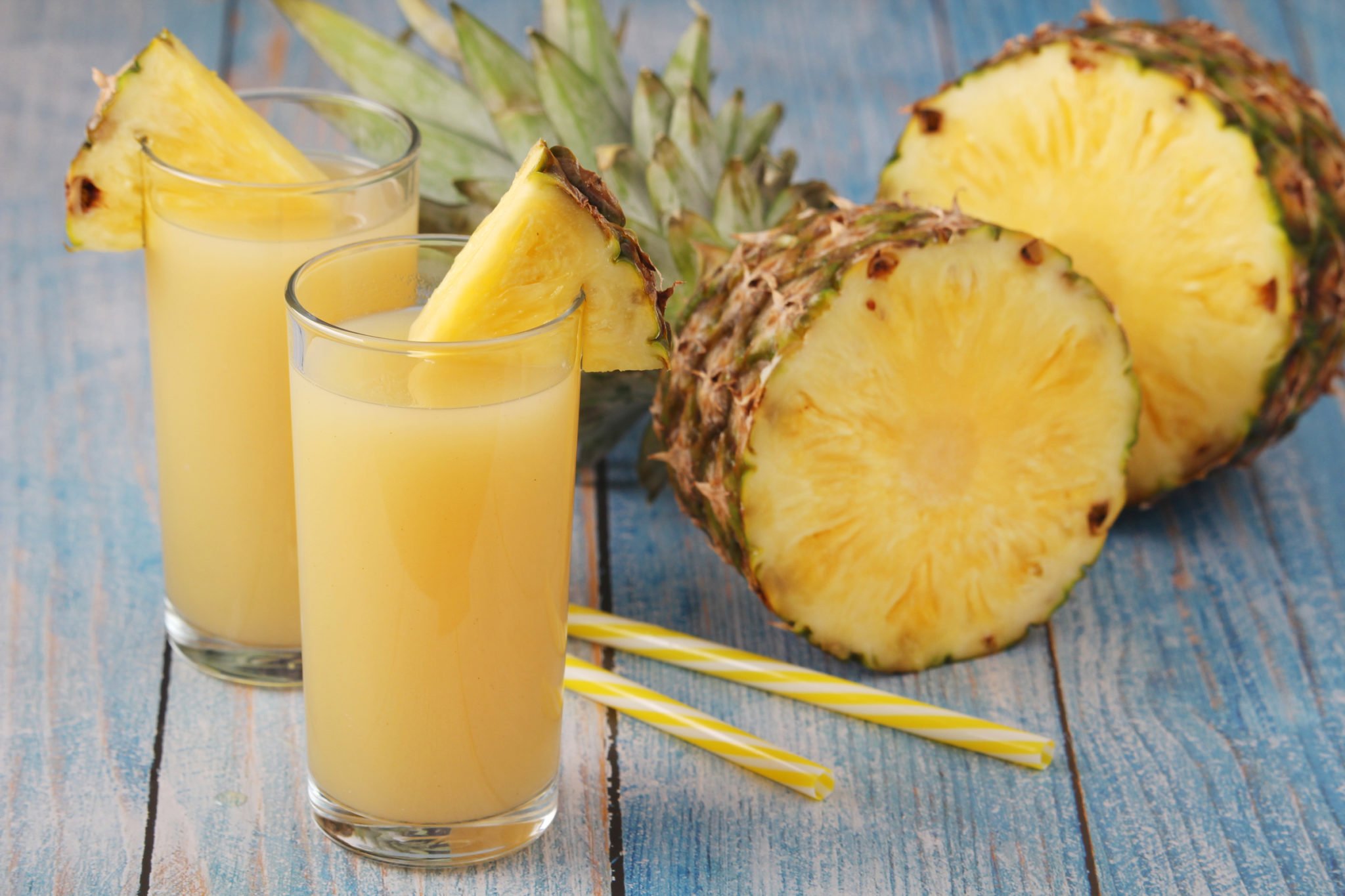 pineapple juice in glasses beside fresh pineapples