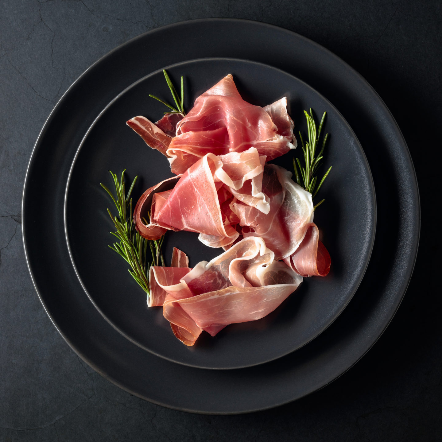 prosciutto slices with rosemary on plate