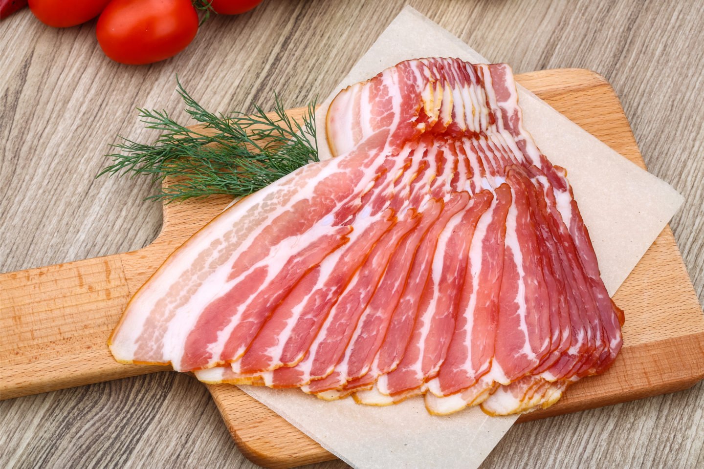slices of raw bacon on cutting board