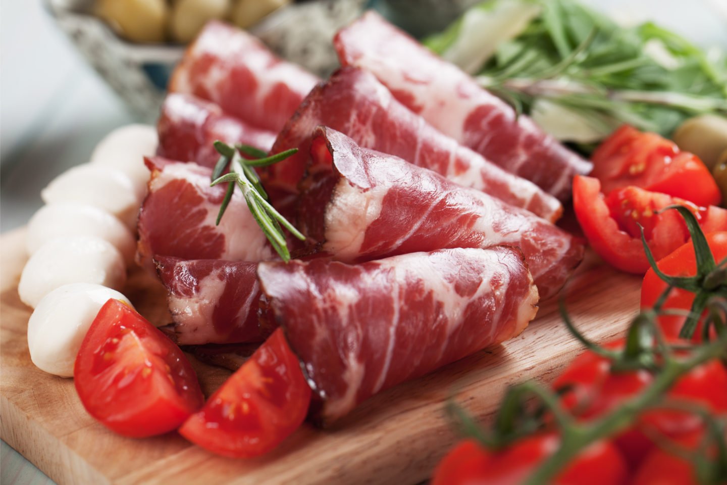 rolls of capicola on cutting board