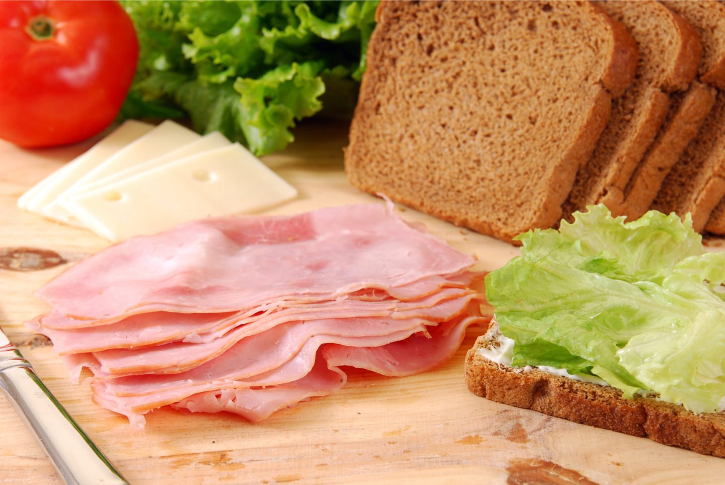 slices of deli ham being made into sandwich