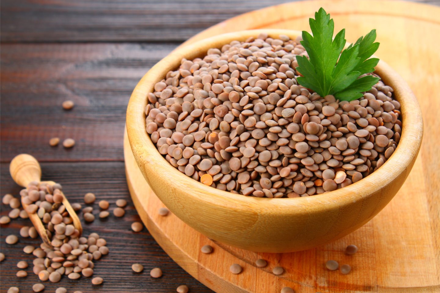 raw lentils in wooden bowl with wooden scoop