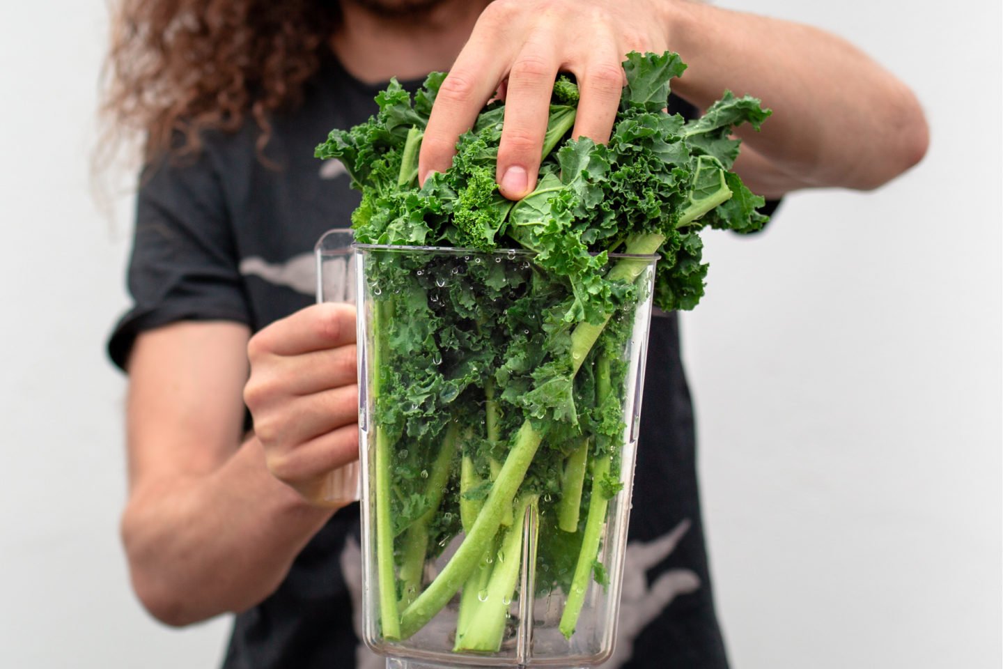 man putting kale lettuce into blender