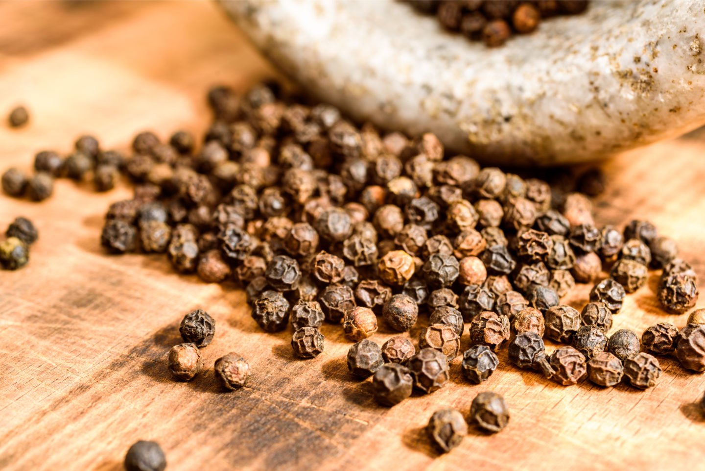 Pile Of Tellicherry Peppercorns On Cutting Board