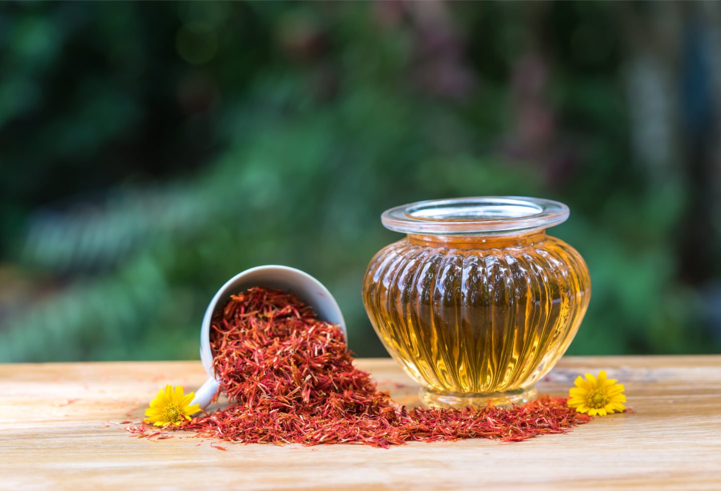 Safflower Oil In Glass Bottle Beside Safflowers