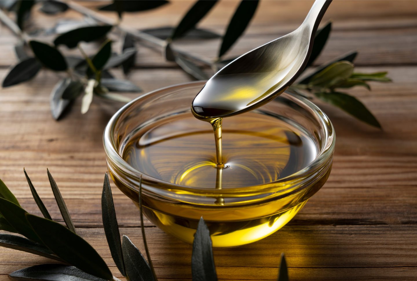 spoonful of olive oil dripping onto bowl