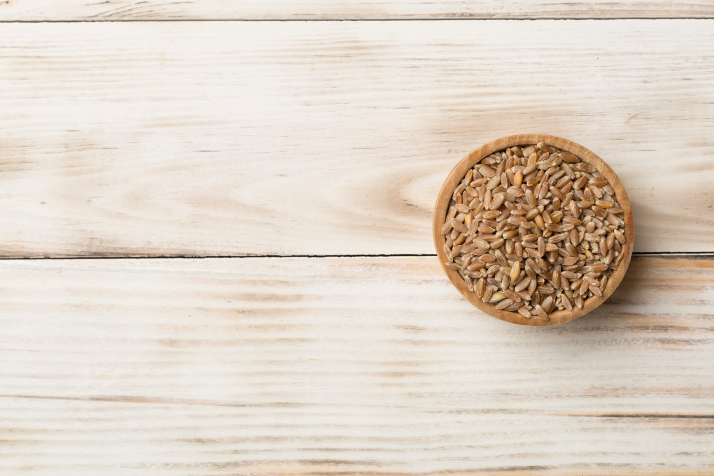 Uncooked Farro In Bowl On Wooden Surface