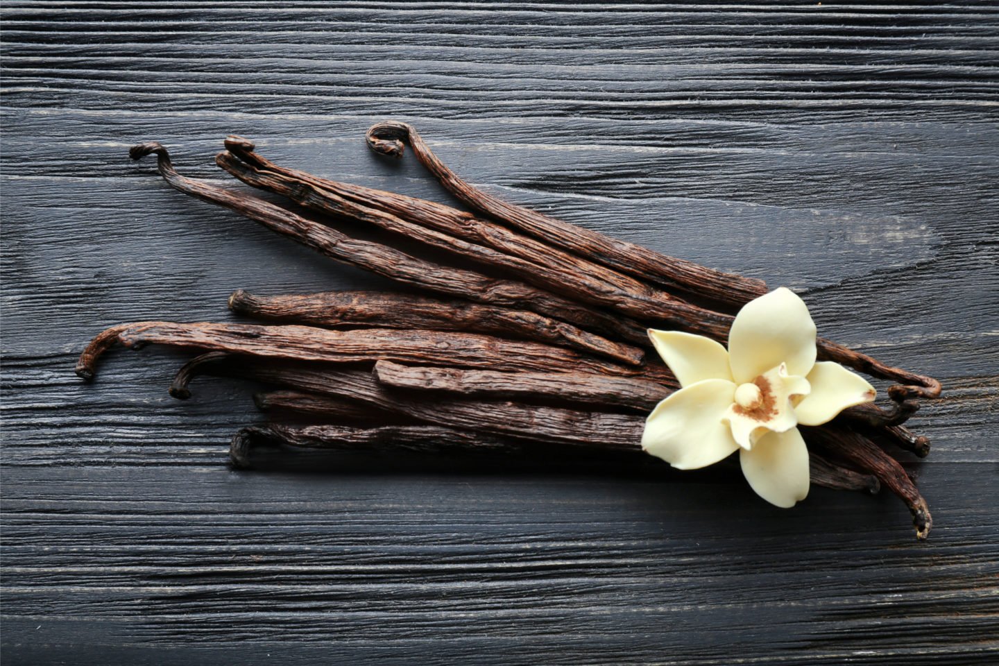 vanilla pods and flower on dark wooden surface
