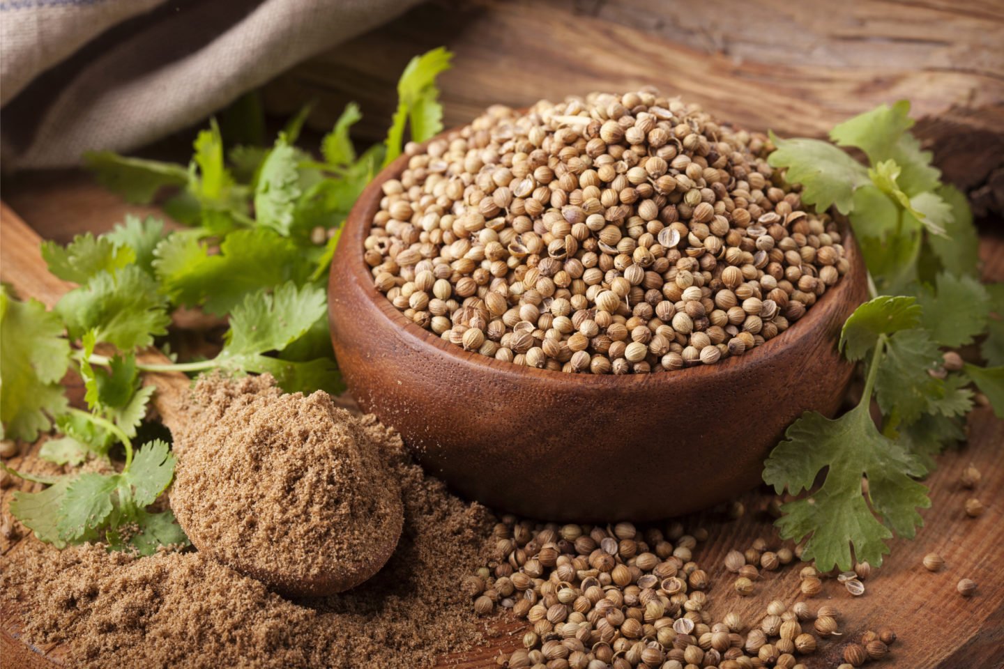 Whole And Ground Coriander Seed With Leaves On Wooden Surface