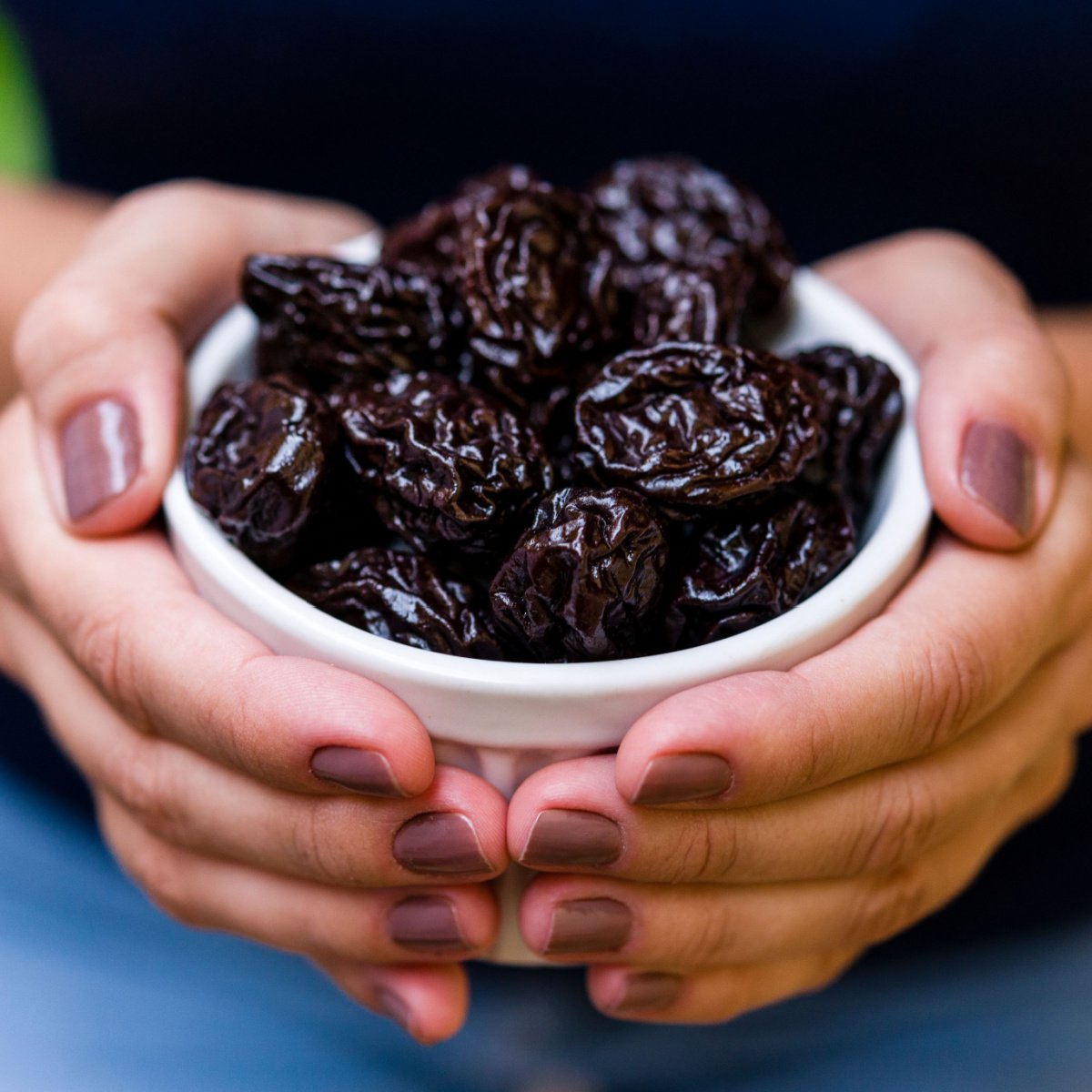woman holding bowl of prunes