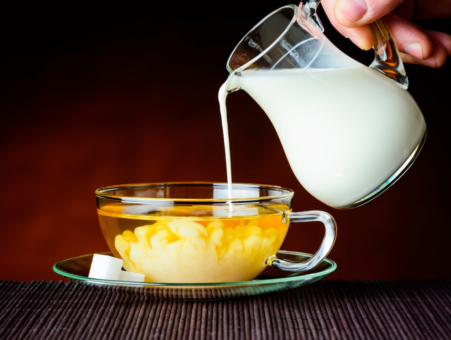 pouring milk into a cup of jasmine tea