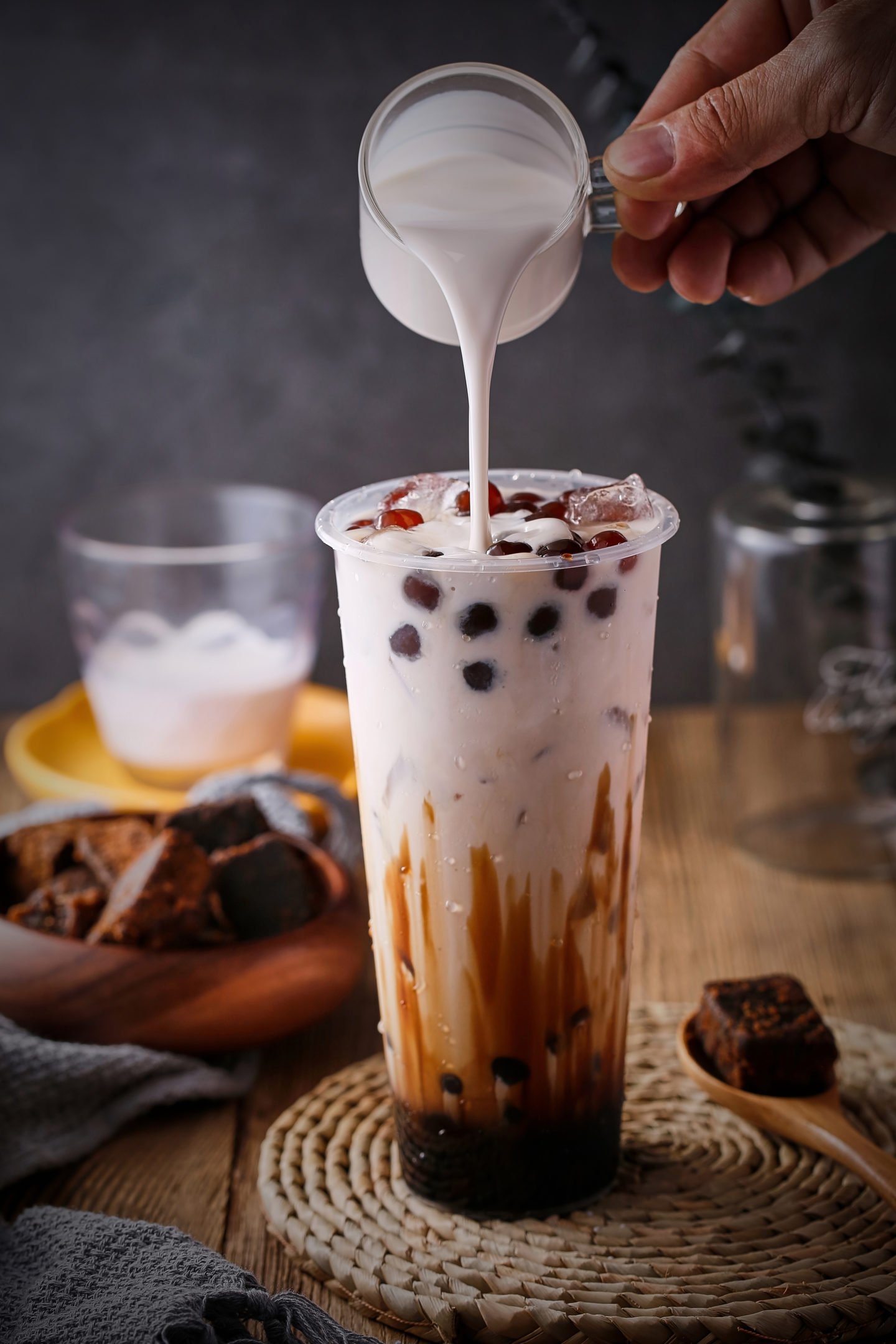 Pouring Milk Into Glass Of Black Tea And Boba