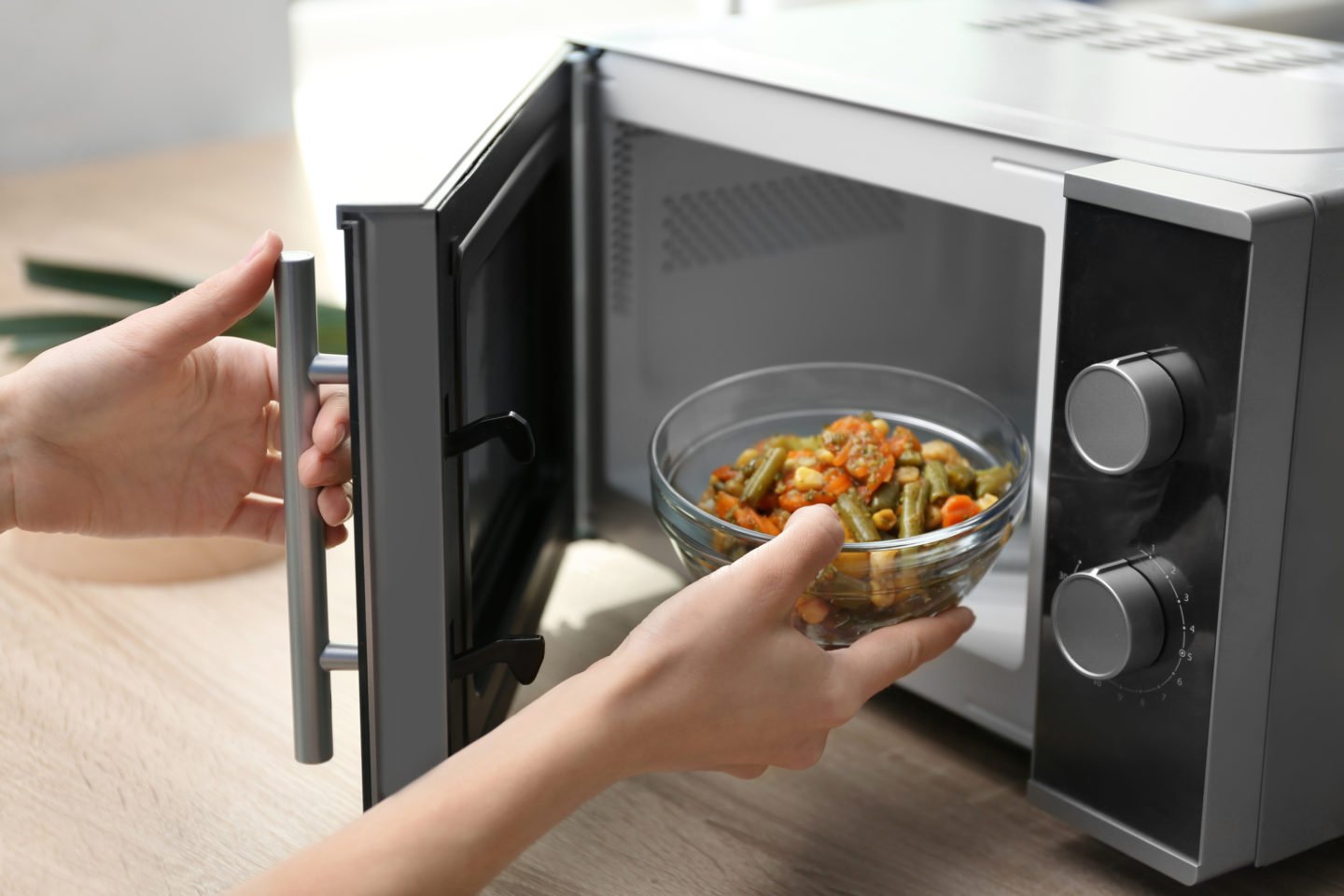 Woman Heating Up Food In Glass Bowl In Microwave Oven