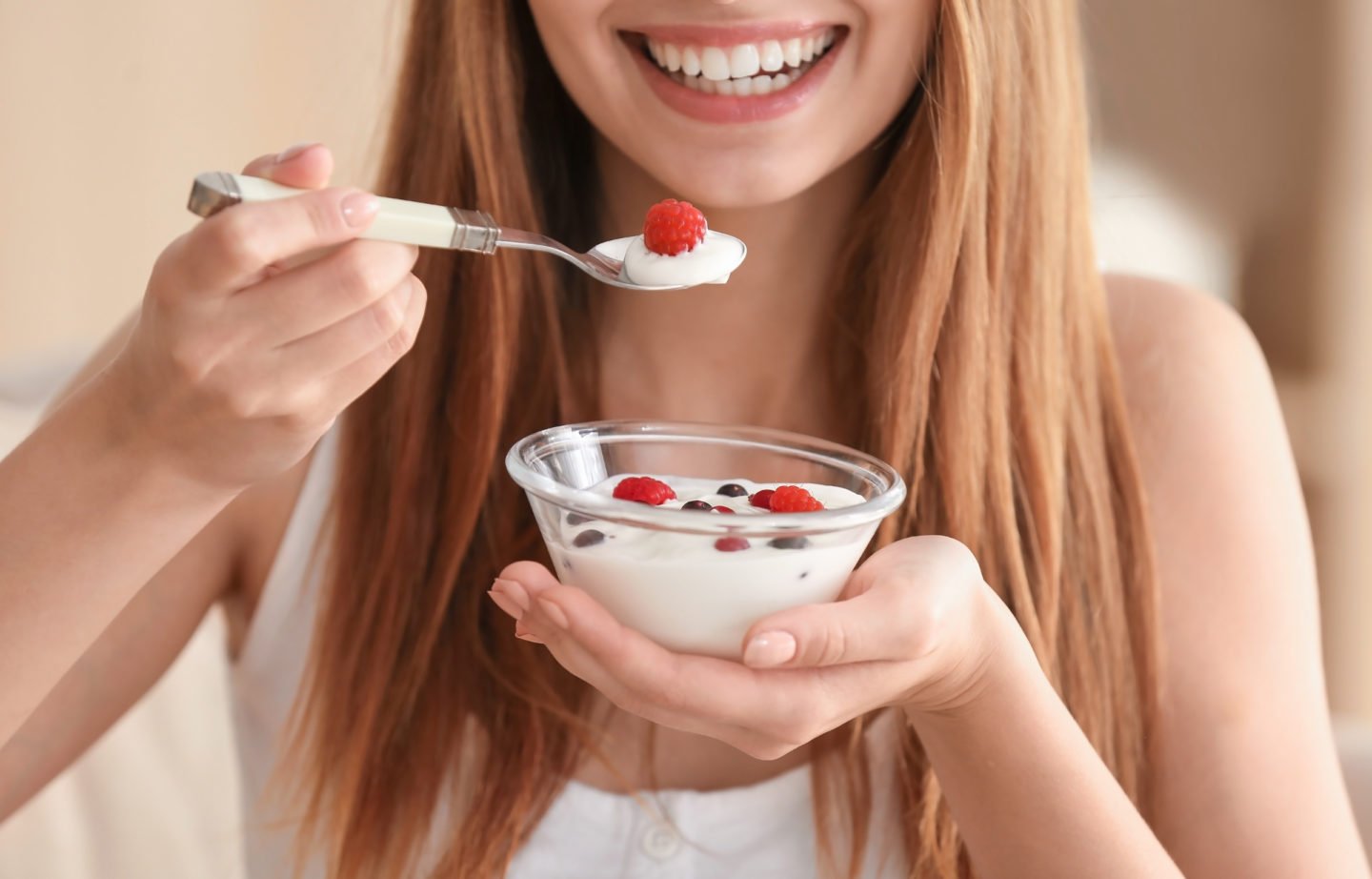 young woman eating yogurt with fresh fruits