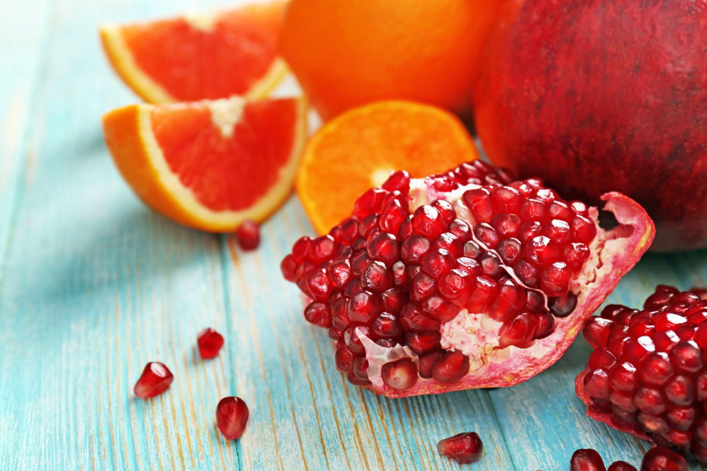 pomegranate seeds and whole fruit with citrus fruits in the background