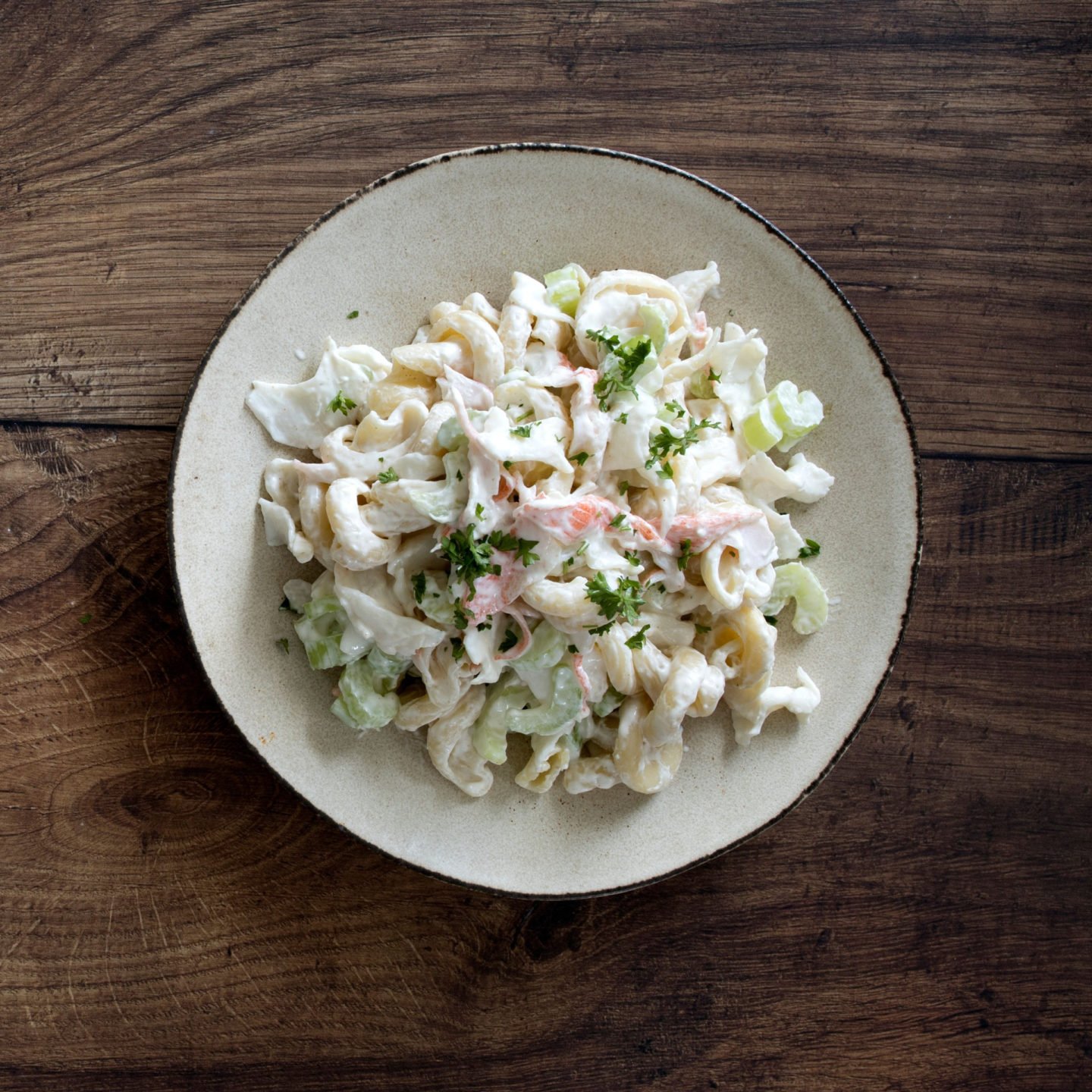 a plate of crab pasta salad on a wooden table