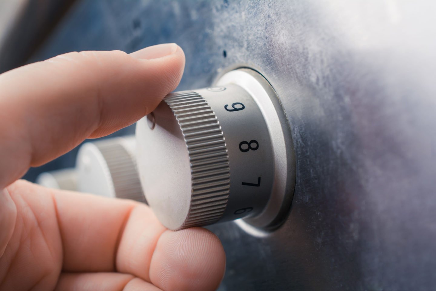 hand holding stove top knob for temperature control